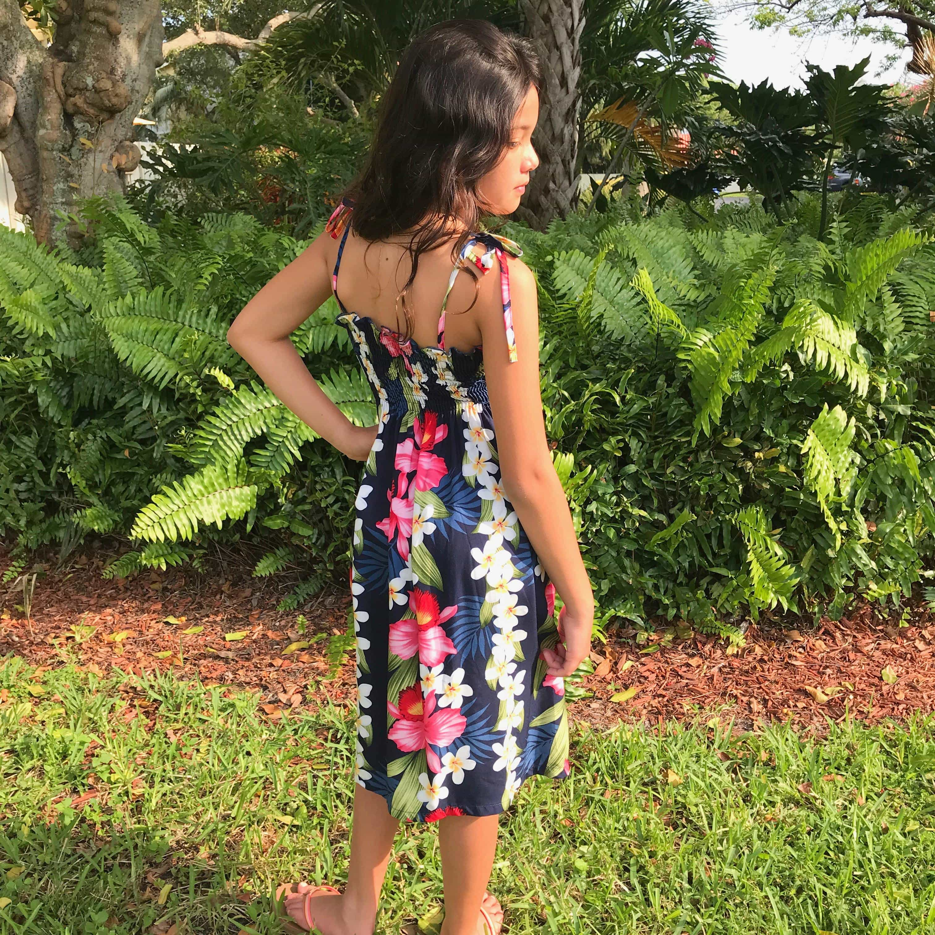 Young girl wearing a blue Hawaiian  dress with pink orchids and white plumeria flowers | Aloha Products USA