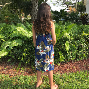 Back view of a young girl wearing a Hawaiian tie strap dress navy color with large white orchid flowers