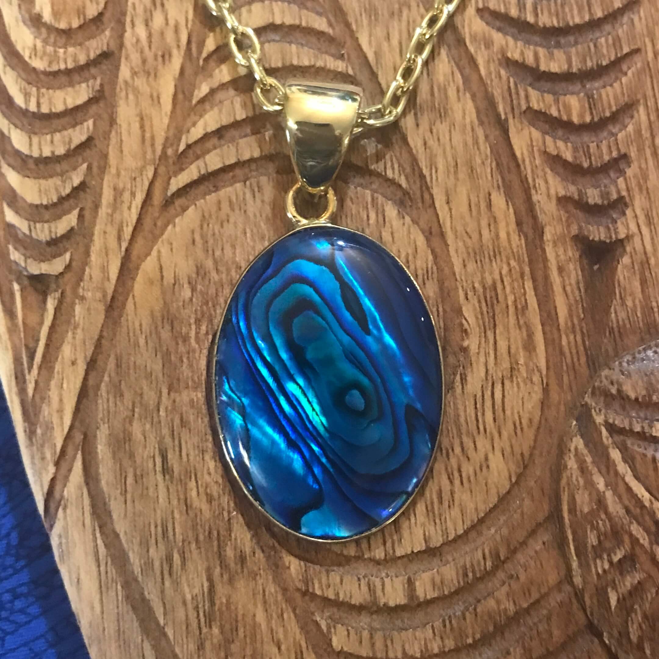 Close up view of a blue abalone oval shell pendant with alchemia gold setting | Aloha Products USA