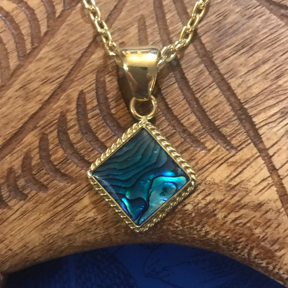 Close up view of a blue abalone shell pendant necklace square shaped with alchemia gold rope trim