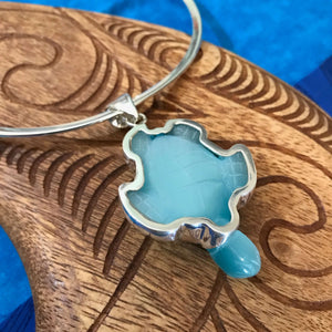 Back view of a blue fiber optic carved turtle pendant in a stirling silver setting