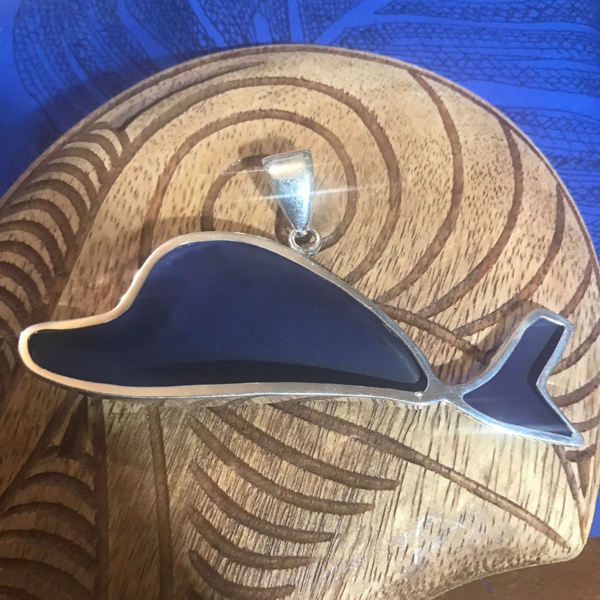 Back view of a blue beach glass pendant that is dolphin shaped