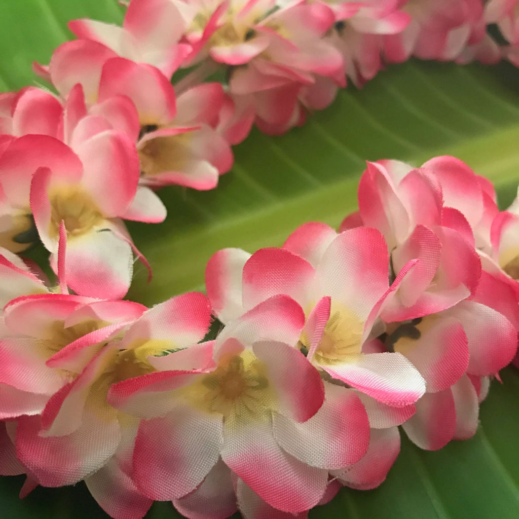 Close up view of a Hawaiian silk head lei with pink and white mini plumeria flowers