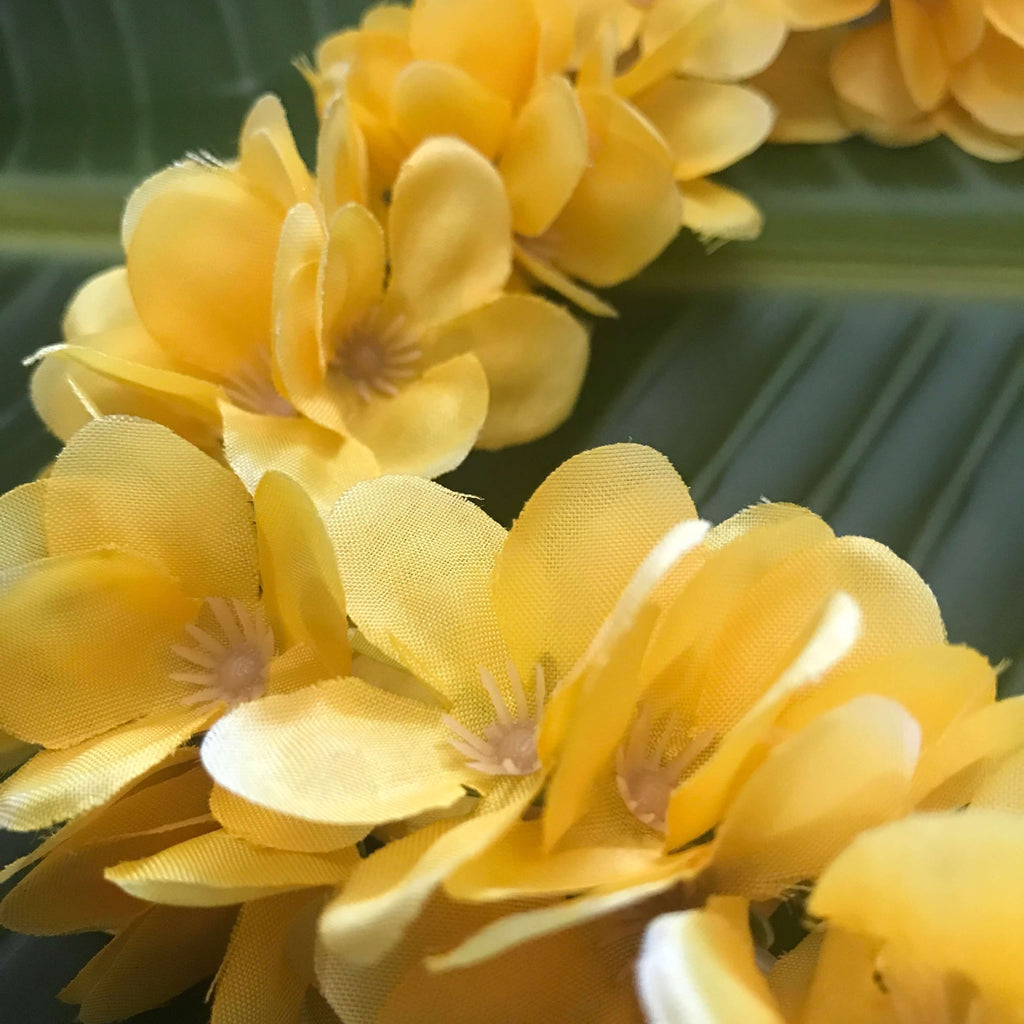 Close up view of Hawaiian silk head lei elastic headband with mini yellow plumeria flowers