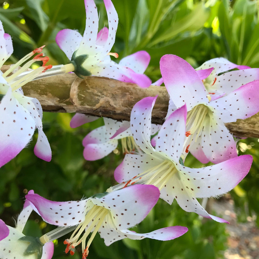 Close up view of a purple and white lily flower Hawaiian silk lei | Aloha Products USA