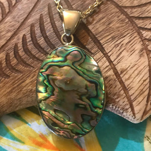 Close up view of a natural abalone oval shaped pendant set on alchemia gold | Aloha Products USA