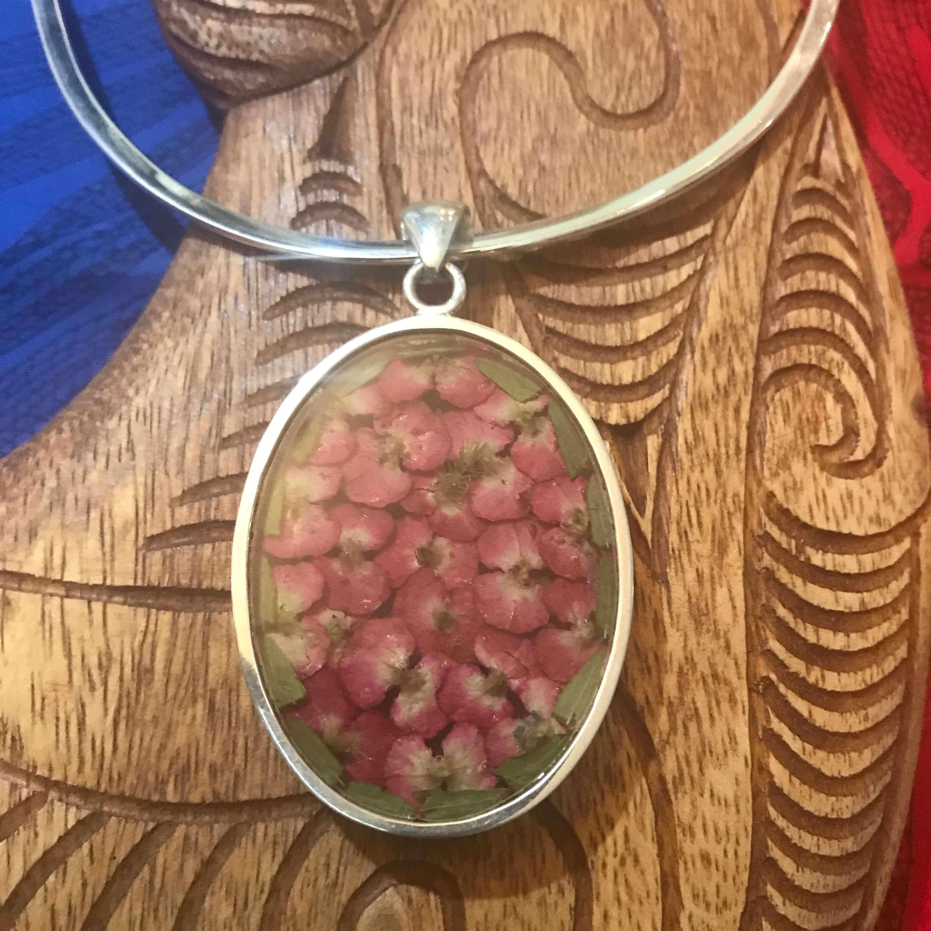 Back view of a dried red flower resin pendant necklace in stirling silver